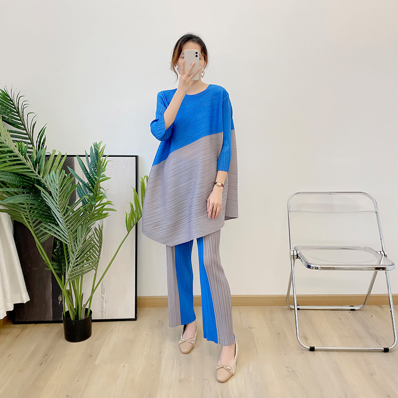 New color blocked seven quarter sleeve angled top with pleated suit and contrasting straight leg pants two-piece set