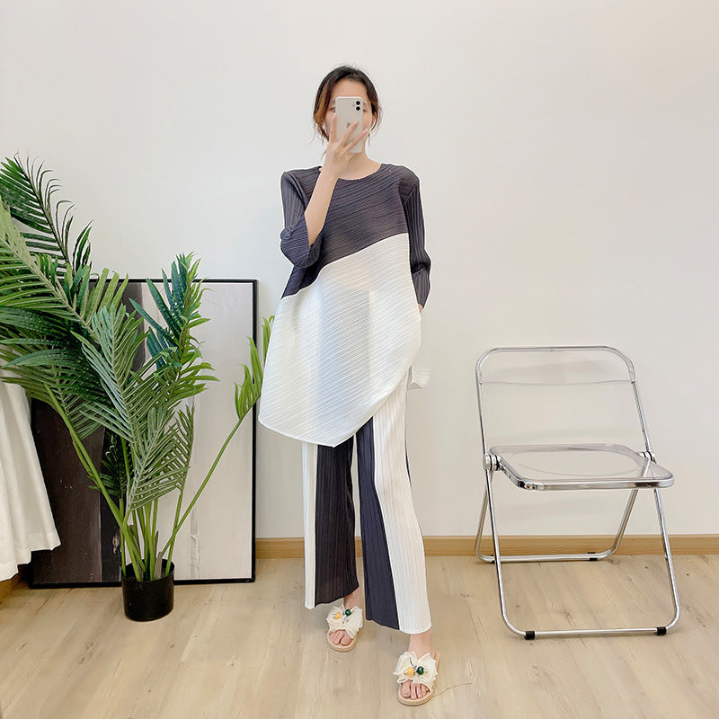 New color blocked seven quarter sleeve angled top with pleated suit and contrasting straight leg pants two-piece set